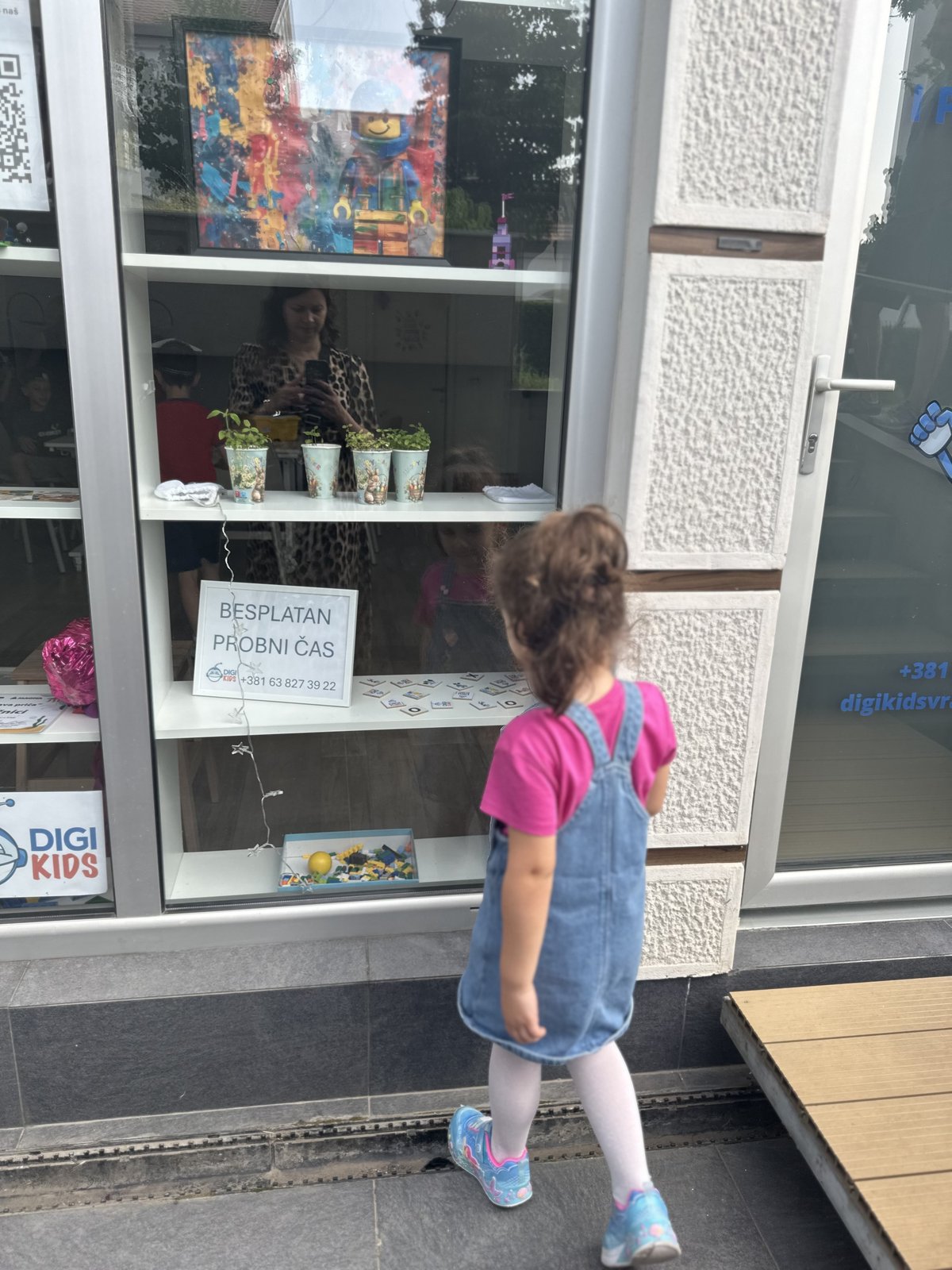 Devojčica gleda kroz izlog DigiKids — besplatan probni čas